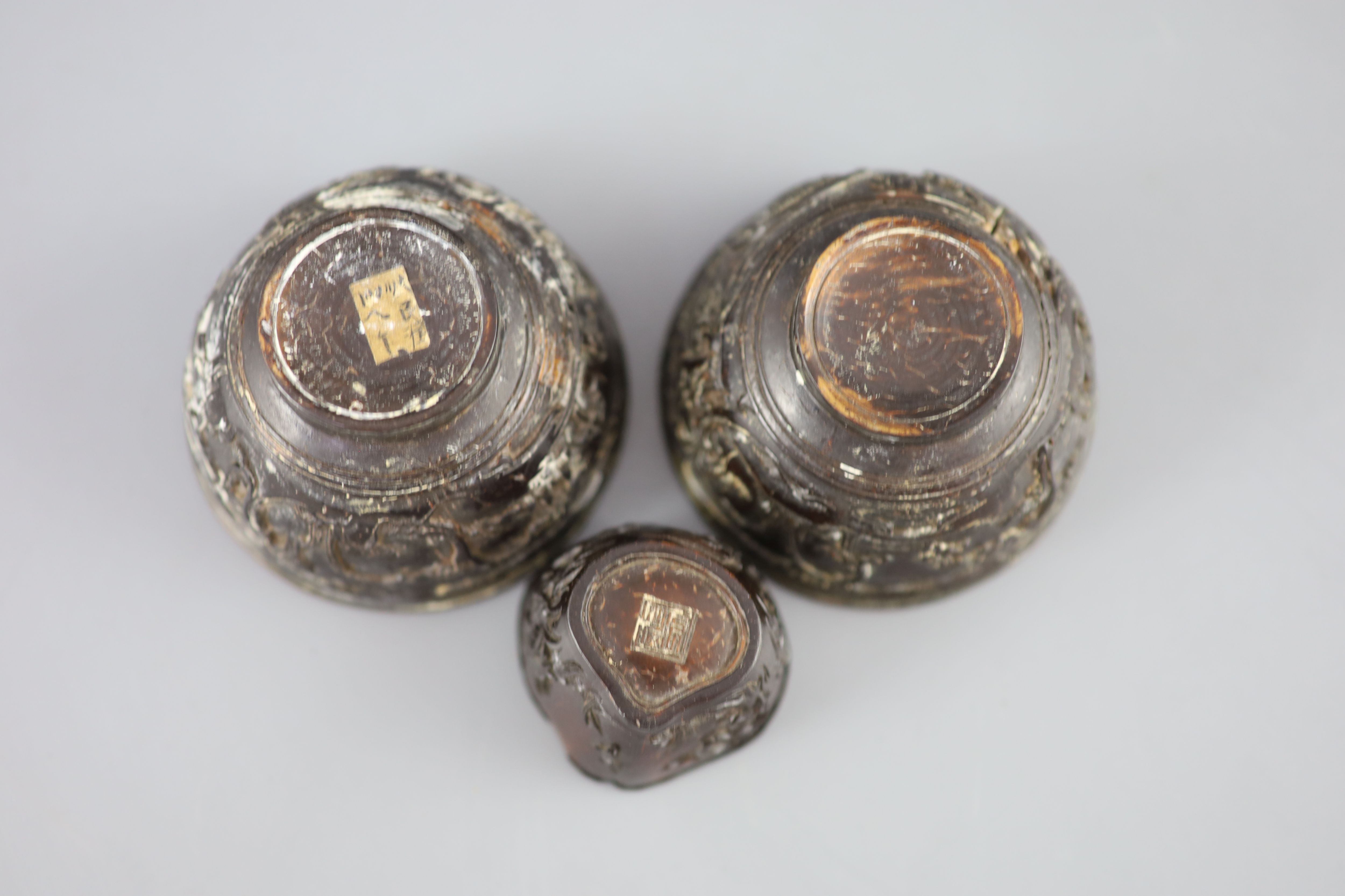 A pair of Chinese coconut landscape cups and a similar peach-shaped cup, 18th/19th century,
